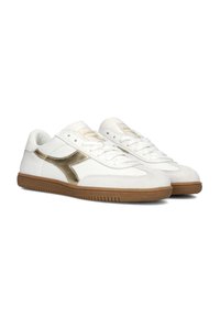 Scarpe sportive bianche con una tomaia in suede e pelle testurizzata, dettagli dorati e una suola in gomma naturale con un motivo rigato.