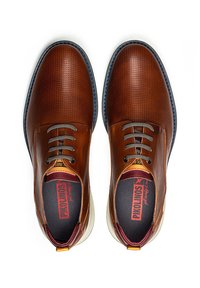 Zapatos de piel marrón con una superficie texturizada, suela azul en contraste, cordones grises y un logo destacado en las plantillas. Diseño de punta redondeada.