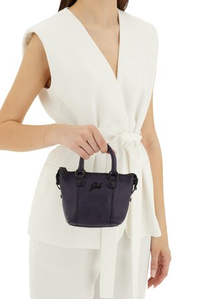 Piccola borsa a tracolla in pelle viola con dettagli e manici neri, caratterizzata da una superficie testurizzata e un logo. Tenuta in mano contro una maglietta bianca.