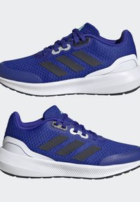 Scarpe da atletica di colore viola con tomaia in rete, strisce nere e suola in gomma bianca. Presentano un collo imbottito e una suola intermedia ammortizzata.