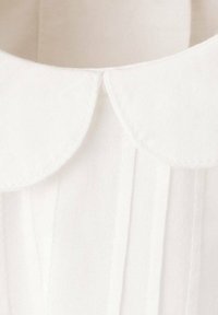 Bela bluza z zaobljenim ovratnikom, z nežnimi gubami in gladko teksturo. Tkanina je lahka in fino tkana.