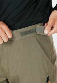 Pantalons hommes couleur vert olive avec une finition texturée, dotés d'une taille en Velcro et de poches latérales, affichant un design robuste et des lignes épurées.