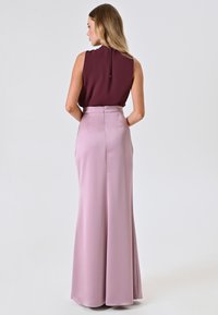 Bordeaux-farbenes ärmelloses Oberteil mit hohem Kragen, kombiniert mit einem langen, hellrosa Satinrock mit taillierter Passform und seitlichem Reißverschluss.