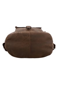 Sac à dos en cuir marron vu du dessous, montrant une base arrondie avec une couture centrale et une partie du rabat supérieur avec une boucle.