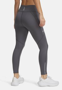 Leggings de sport gris avec une taille haute, des accents texturés, des détails perforés et des rayures blanches contrastantes sur les côtés.