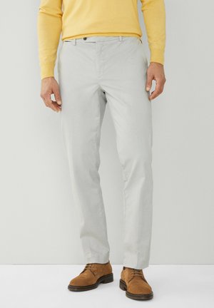 Pantalones gris claro de tela suave, con corte recto, bolsillos frontales y cinturilla con pasadores, combinados con zapatos de ante marrones.