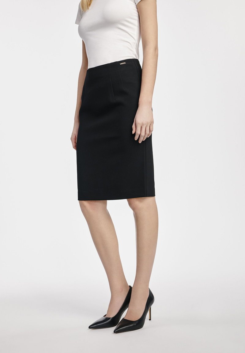 Czarna spódnica ołówkowa o prostym designie, długości do kolan, z ukrytym zamkiem błyskawicznym po boku i subtelnym akcentem marki. Dopasowany krój o gładkiej fakturze.