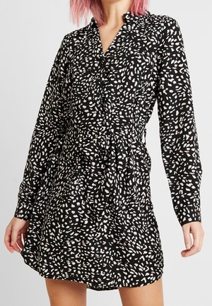 Schwarzes Kleid mit langen Ärmeln, Kragen und tailliertem Schnitt. Verziert mit einem weißen und pinken abstrakten Muster.