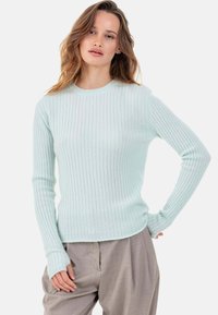 Pull côtelé vert menthe clair avec manches longues et encolure ronde. Le tissu semble doux et légèrement texturé.