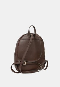 Zaino in pelle marrone con finitura testurizzata, dotato di spallacci regolabili, tasca con zip e semplici dettagli metallici.