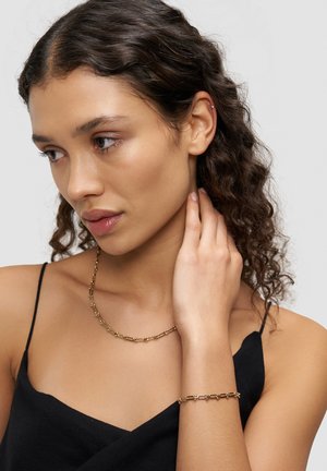 Gold-tone jewelry set featuring a beaded necklace and bracelet, with a smooth texture and elongated, interlocking shapes.