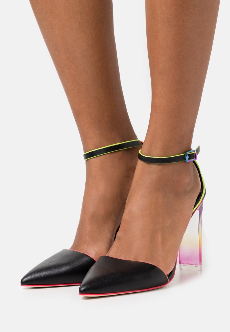 Chaussures à talons hauts en cuir noir avec bout pointu, bride de cheville jaune fluo et talon transparent dégradé passant au rose.