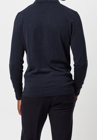 Dunkelblauer Langarmpullover mit Kragen, der eine glatte Textur sowie gerippte Bündchen und Saum aufweist, von hinten betrachtet.