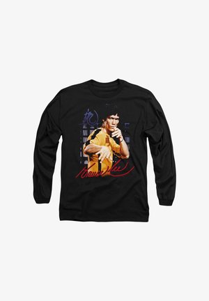 Schwarzes Langarmshirt mit einem farbigen Bild einer Person in einem gelben Outfit. Mit Text und Unterschrift in Rot und Blau.