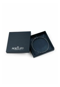 Collana d'argento con delicate maglie, esposta in una scatola quadrata blu navy con superficie testurizzata e il logo del marchio in argento.