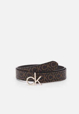 Brązowy skórzany pasek z powtarzającym się wzorem "CK" i srebrną metalową klamrą "ck", zwinięty na białym tle.