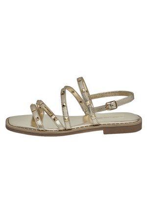 Flad gylden sandal med flere tynde remme, små pyramide-nitter, en sidelås og en brun sål.