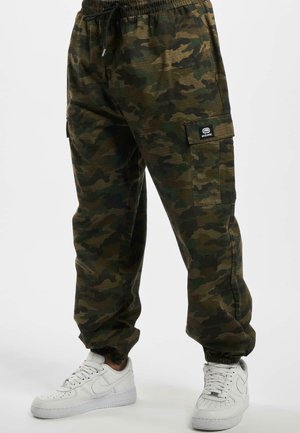 Heren camouflage cargobroek met elastische boorden, aantrekkoord in de taille en zijzakken, gecombineerd met witte sneakers.