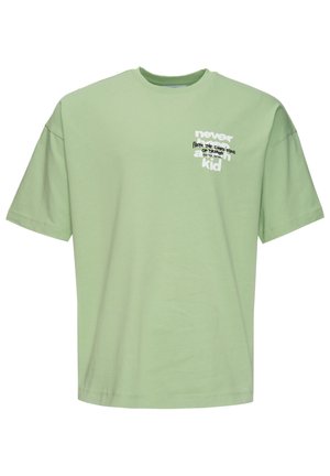 Mint green t-shirt with a relaxed fit, short sleeves, and a crew neckline. Features white text graphic on the front. Smooth cotton texture.