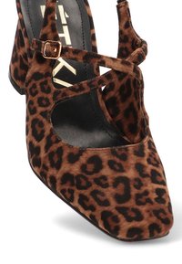 Zapato de tacón alto con print de leopardo, puntera cuadrada, tela texturizada en marrón y negro, y detalle de correa en el tobillo. Diseño de tacón grueso.