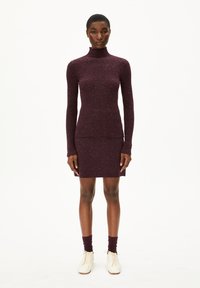 Bordeaux ribbel brei jurk met hoge kraag, aansluitende lange mouwen en een mini-lengte. Gecombineerd met witte veterschoenen en bijpassende sokken.