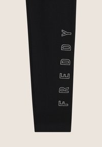 Leggings neri con un design aderente e una texture morbida, con la scritta "FREDDY" ricamata verticalmente in bianco sul lato.