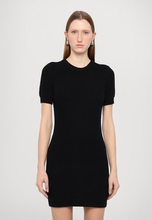 Robe noire en maille côtelée avec des manches courtes bouffantes, un col rond et une silhouette ajustée, offrant une texture douce et un design minimalist.