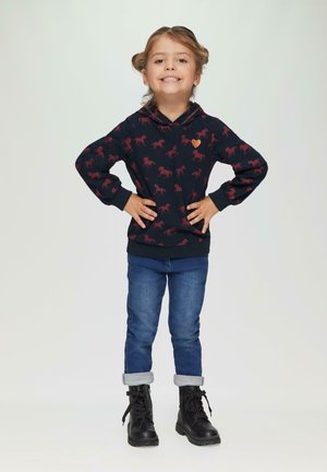 Marineblauwe hoodie met rood paardenpatroon, voorzien van een kangoeroezak en een klein hartaccent. Gepaard met gekrulde spijkerbroek en zwarte laarzen.