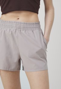 Šviesiai pilki, su elastingu juosmeniu šortai su šoninėmis kišenėmis. Audinys atrodo lygus ir lengvas, sukurtas patogumui ir judėjimo laisvei.