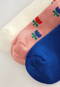 Drei Paar Socken: weiß, rosa mit floralen Mustern und einfarbig blau. Sie verfügen über ein strukturiertes Gewebe und ein abgerundetes Zehendesign.