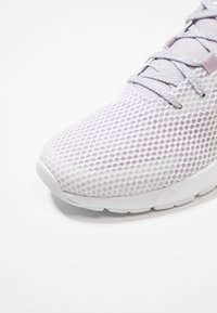 Chaussure de sport en mesh violet clair avec une surface texturée, dotée d'une semelle blanche et de lacets blancs, un bout arrondi et un design respirant.