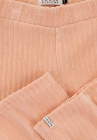 Lichtroze, geribbelde stof met een zachte textuur. Voorzien van een elastische tailleband en een klein label met de tekst "LOOXS" zichtbaar. Over het geheel genomen een gladde afwerking.