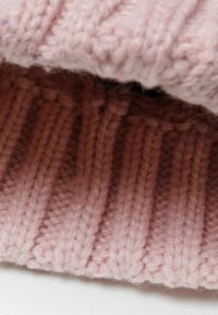 Knit hat with a soft, fluffy texture in light pink, featuring vertical ribbed patterns. The fabric has a cozy, warm appearance.