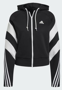 Sweat à capuche zippé Adidas noir et blanc avec une capuche, des cordons, des bandes en chevron sur les manches et le logo Adidas sur la poitrine.