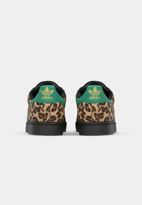 Sneaker con stampa leopardata, dettagli neri, logo verde e suole nere piatte. Materiale morbido con finitura testurizzata sul retro.