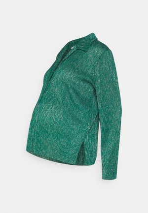 Zöld kismama ing texturált mintával, galléros kialakítással, hosszú ujjakkal és oldalsó hasítékokkal a kényelmes mozgás érdekében.