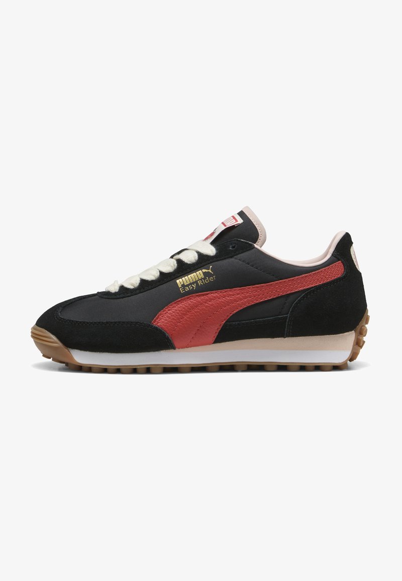 Svarta och röda sneakers i mocka och nylonmaterial, med en vit mellansula, beige tunga, guldlogotyp och gummisula med nubb.