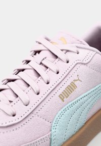 Tenisky Puma s horní částí z jemného růžového semiše, tyrkysovými detaily, zlatým logem a plochými tkaničkami. Mají strukturovanou podrážku pro lepší grip a pohodlí.