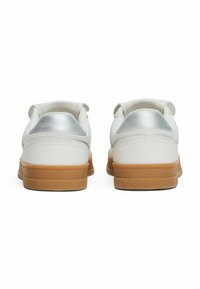 Baskets en cuir blanc avec des accents argentés au niveau des talons et des semelles en caoutchouc beige. Logo "TOMMY JEANS" embossé à l'arrière.