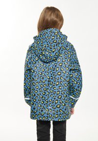 Impermeabile blu con stampa leopardata verde e nera, dotato di cappuccio e maniche lunghe. Texture liscia, design leggero e dettagli riflettenti.
