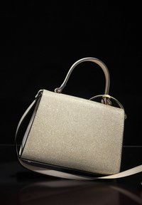 Bolso con textura dorada y diseño estructurado, que cuenta con un asa superior, una correa para el hombro y un ribete negro en contraste.