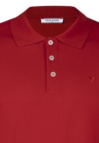 Rød polo-shirt lavet af tekstureret stof med klassisk krave, tre knapper og et lille broderet logo på venstre bryst.