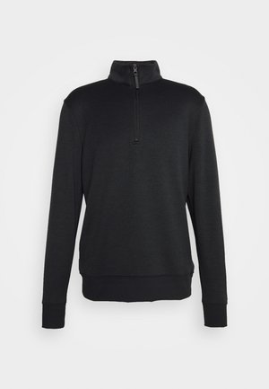 Sudadera negra con cremallera en un tejido texturizado, que presenta un cuello alto y puños y dobladillo acanalados, con un ajuste relajado y un diseño minimalista.