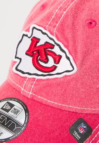 Ružový textilný klobúk s logom Kansas City Chiefs v červenej a bielej výšivke, s kontrastným prešívaním a značkovým štítkom na šilt.