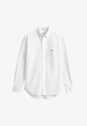 Camisa blanca de manga larga fabricada en algodón. Cuenta con un cuello abotonado, un bolsillo en el pecho izquierdo y un dobladillo curvado. Textura suave.