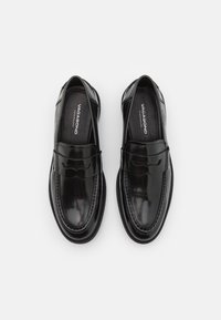 Paire de mocassins noirs en cuir avec un design classique à bride penny et des semelles intérieures brandées, vus de dessus sur fond blanc.