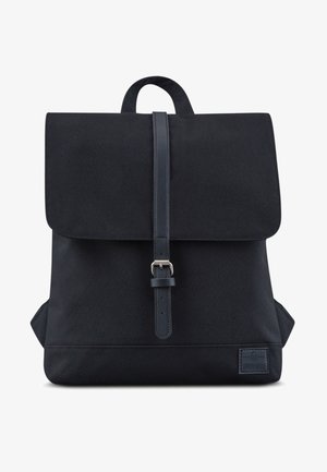 Sac à dos noir en toile avec une fermeture à rabat, une sangle réglable, une boucle en métal et un patch logo brodé. Présente une forme structurée et des poches latérales.