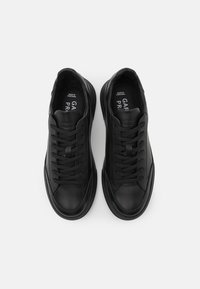 Sneaker in pelle nera con punta arrotondata, chiusura con lacci, suola imbottita e marchio sulla soletta, caratterizzati da superfici lisce e testurizzate.