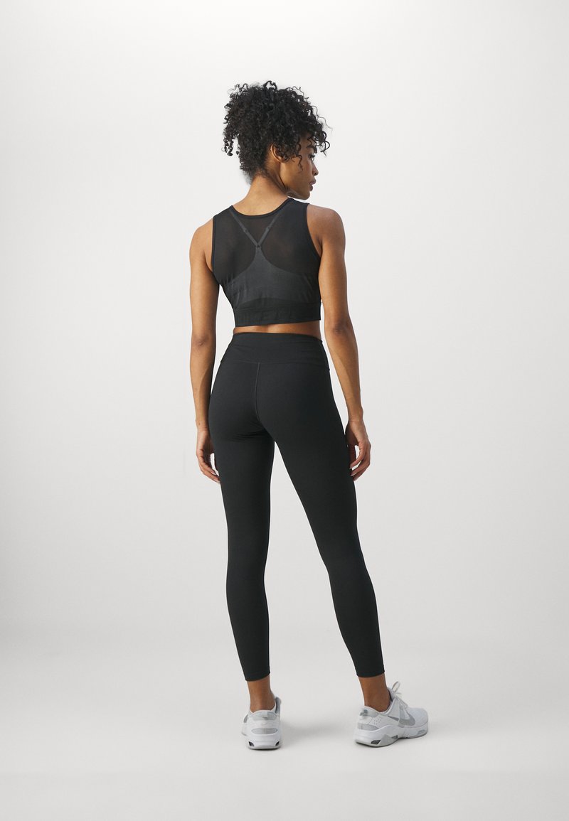 Soutien-gorge de sport noir avec un panneau en maille et des bretelles ajustables, associé à un legging noir taille haute. Texture lisse, design ajusté.