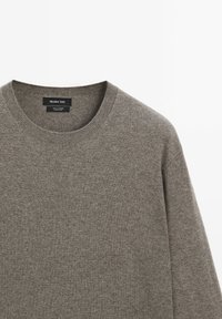 Grauer Rundhalsausschnitt-Pullover aus 100% Kaschmir. Bietet eine glatte Textur mit gerippten Kanten am Halsausschnitt und den Bündchen. Etikett sichtbar.